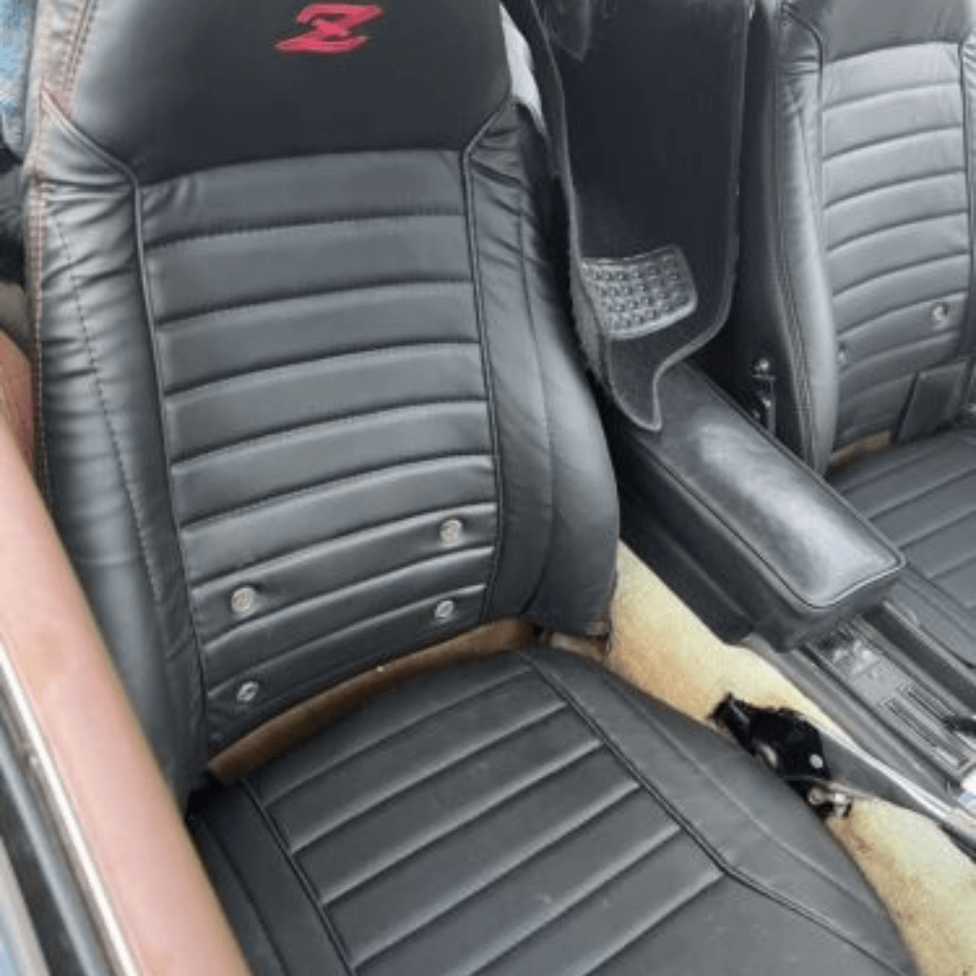 Detailed view of black leather seat covers in a Datsun 260Z 240z 280z, featuring a red 'Z' logo, precision stitching, and padded design for added comfort.