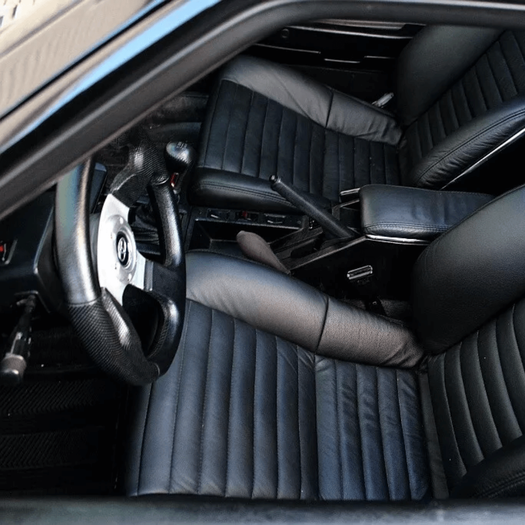 Another view of the Toyota Celica 3rd generation (1981-1985) interior with black leather sports seat covers. This angle highlights the ribbed seat design and sleek upgrade, perfectly tailored for the Celica’s classic interior.