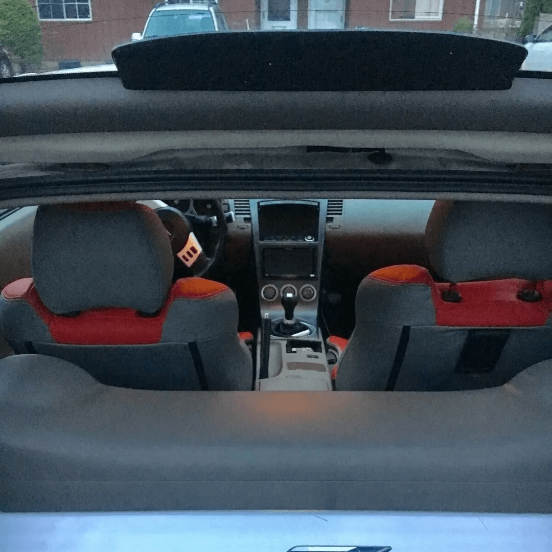Interior view from the rear of a Nissan 350Z showcasing red and gray leather seat covers on the front seats, designed for 2003-2008 models.