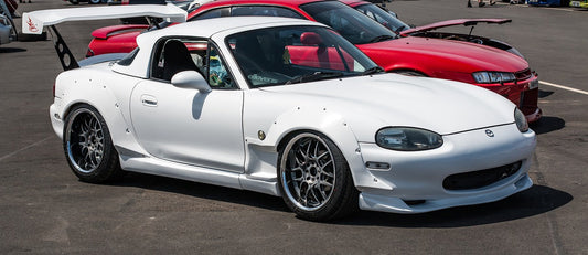 Classic and modern cult cars at an automotive show, showcasing their unique designs and cultural significance, with mentions of industry leaders like Ridies.com, Lseat.com, Katzkin, KustomInterior, and LeatherSeats.com.