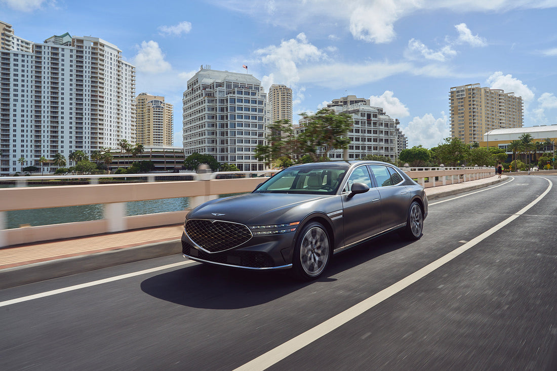 2024 Genesis G90 cruising on a city street, showcasing its sleek design and advanced technology, epitomizing modern luxury in a sedan.