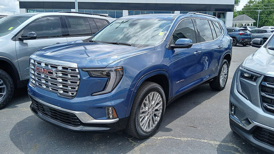 024 GMC Acadia driving on a highway, showcasing its new, longer design and the robust performance of its turbocharged engine.