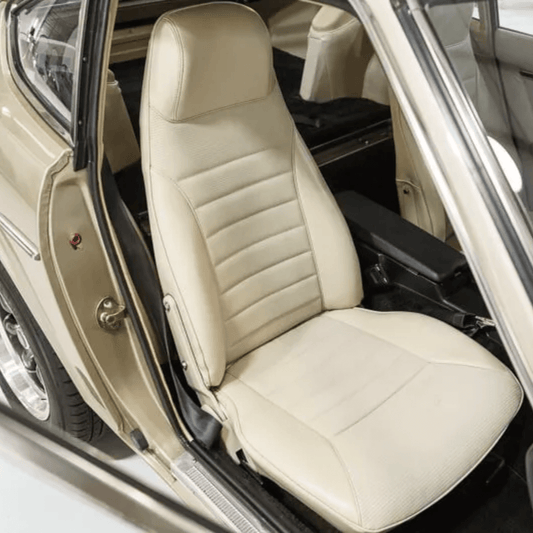 Datsun 240Z/260Z/280Z Leather Seat Covers (1970-1978) in beige/cream color, installed on the driver seat of a vintage sports car. The seat design features horizontal stitching patterns with a smooth leather surface, complementing the classic interior of the car.