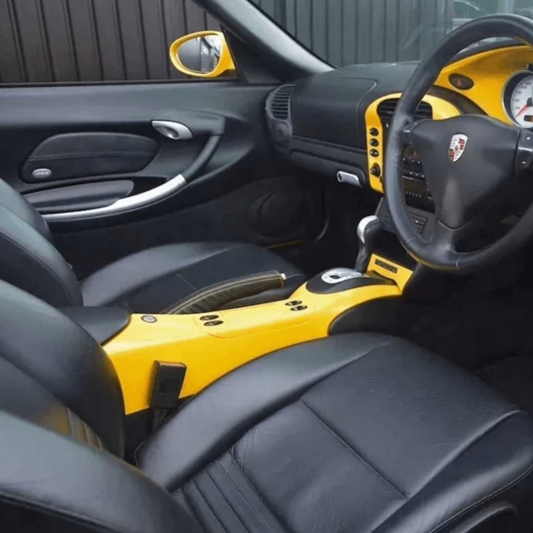 Interior view of a Porsche Boxster 986 (1997-2004) featuring sleek black leather seat covers and a vibrant yellow dashboard.