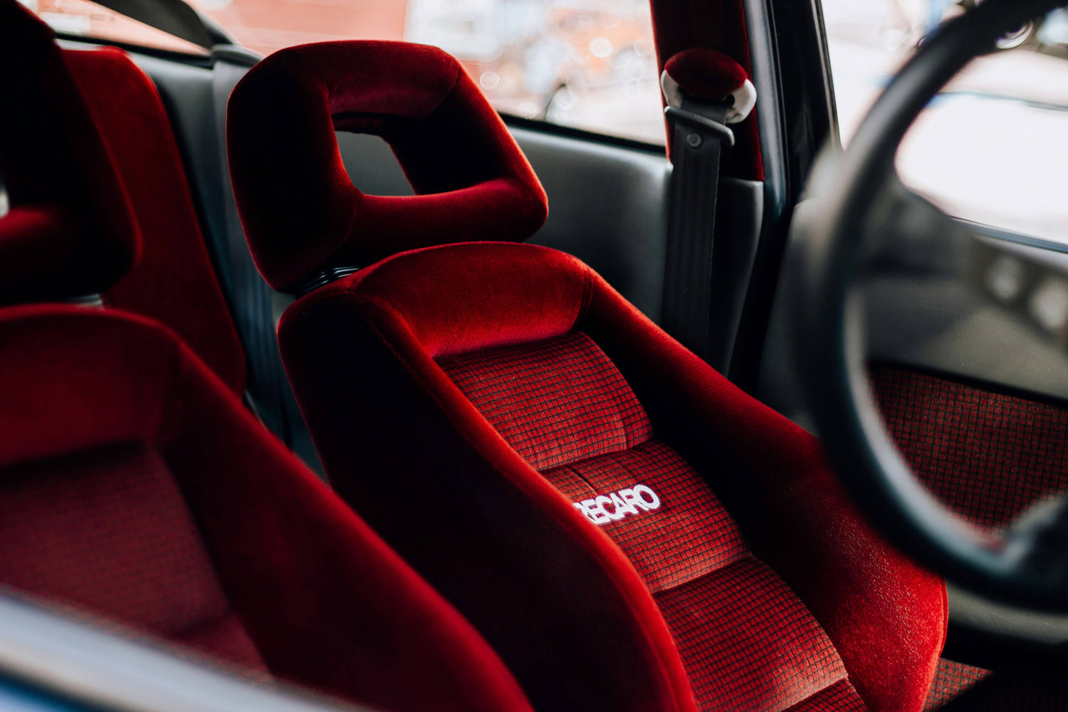 Close-up of Recaro racing bucket seat in a car interior, highlighting the red upholstery and headrest design for optimal support and comfort.